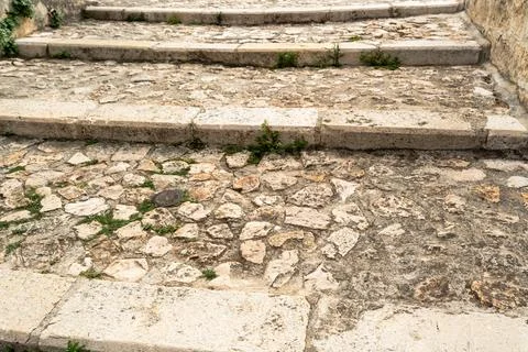 Old limestone staircase with worn stone steps and cobblestones overgrown with Stock Photos