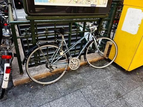 Old locked Puch bicycle chained at a Paris France metro entrance with yello.. Fotos de archivo