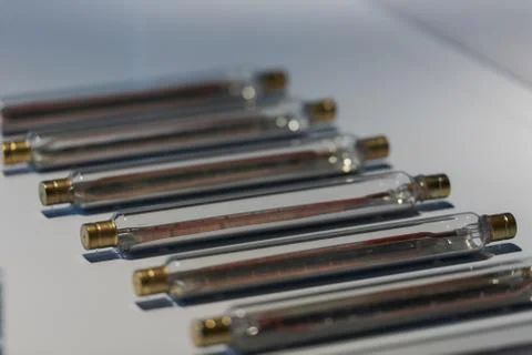Old long light bulbs in form of tubes lying on white table Stock Photos
