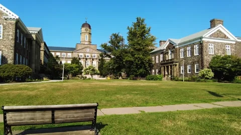 Old looking building university style with a green yard and bench 動画素材 314734436