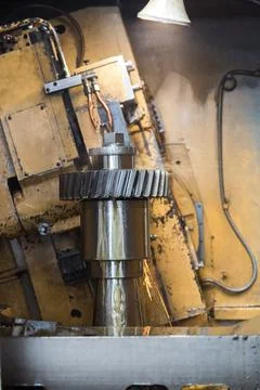 Old machine processes a large metal part. Cutting and cooling of the product. Stock Photos