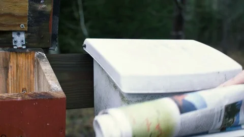 Old mailbox in the forrest being oppened by a hand, that then deliveres a newspa Stock Footage 84658628
