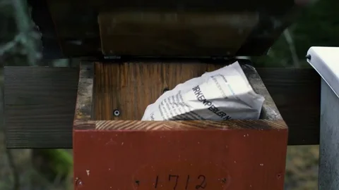 Old mailbox in the forrest being oppened by a hand, that then removes a newspape Stock Footage 84658657