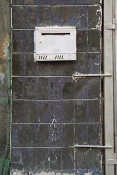 Old mailbox on a peeling column covered with ceramic tiles Stock Photos