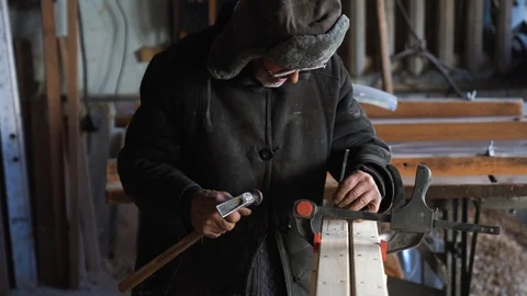 Old male carpenter using chisel to carve wood In workshop Stock Footage 129700352
