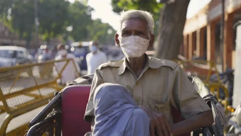 An old male cycle rickshaw driver in uniform sitting  comfortably with face mask Stock Footage 147253684