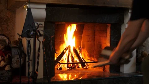 Old man adding more fire wood to fireplace at home in the attic. Evening time.  Stock Footage 123608404