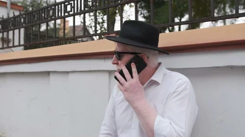 Old man with albinism talking on the phone while sitting next to his house. Stock Footage 148651040