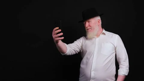 Old man with albinism using phone and taking selfie on black background. Stock Footage 142832160