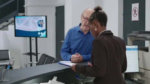 Old man analyzing checkup form papers at hospital reception counter Stock Footage 205115195