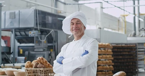 Old man baker portrait looking straight to the camera in a big bakery industry Stock Footage 112139844
