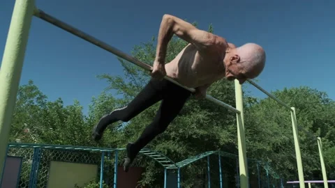 Old man with bare torso does exercise on ground crossbar Stock Footage 201303431