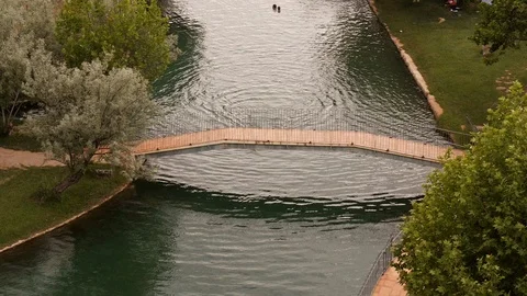 Old man, in a bathrobe with cane crossing bridge over thermal lake Stock Footage 98168574