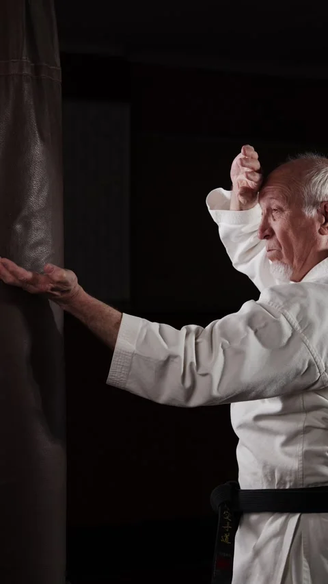 Old man with black belt doing circular punches on the machine Stock Footage 309750897