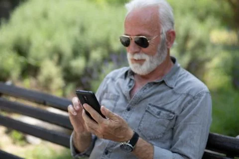 Old man browsing app on smartphone Stock Photos