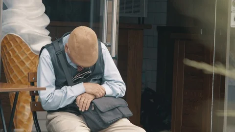 Old man in a cap with a gray mustache and hair fell asleep sitting on a chair Stock Footage 115480764
