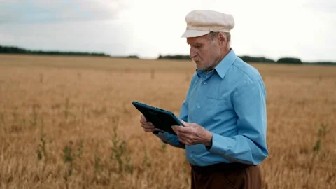 Old man in cap standing at field and using tablet device. Smart farm. Stock Footage 169702320