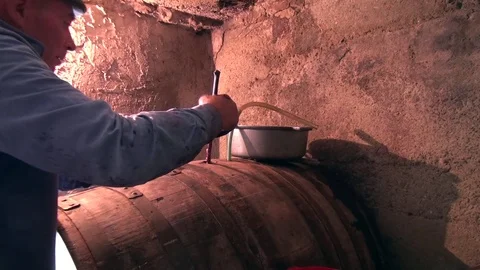 Old man checking wine level and closing a barrel in a cellar Stock Footage 69781914
