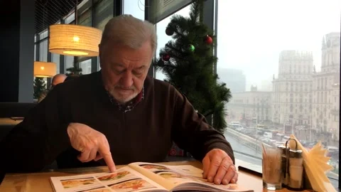 Old man chooses a pizza from the menu pizza in a bar. Stock Footage 169065796