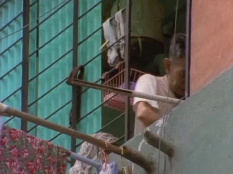 Old man clipping wet clothes to dry outside his apartment window Stock Footage 79878644