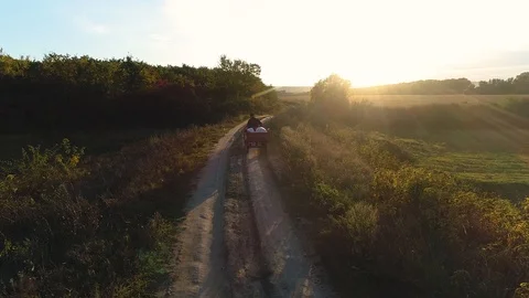 An old man coming from work on a vehicle on a path near a plain, during sunse Stock Footage 113069683
