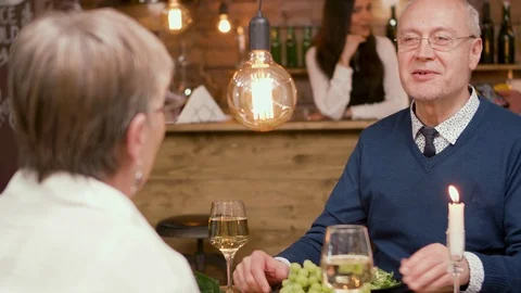 Old man on a date chatting with his partner over a glass of wine Stock Footage 106448313