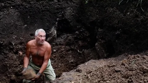 Old man digs a hole in his garden. Video stock 122199671