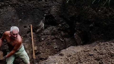 Old man digs a hole in his garden. Video stock 122199791