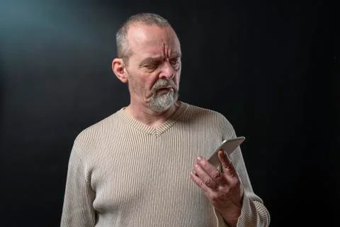 Old man does not understand his smart phone Stock Photos
