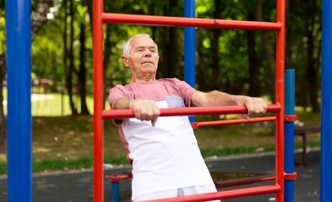 Old man doing exercises on vertical ladder outdoors Stock Photos