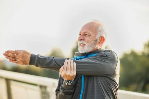 Old man doing physical exercise stretching for a better quality of life Stock Photos