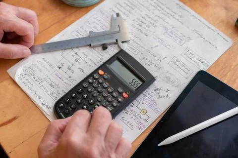 Old man doing some math calculations using digital calculator at his work pla Stock Photos