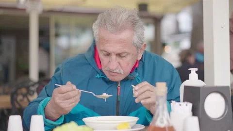 An old man drinks soup and eats bread at restaurant Stock Footage 178532694