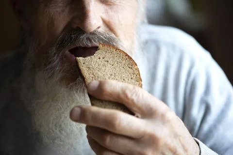 An old man eats bread, face and mouth close up Foto stock