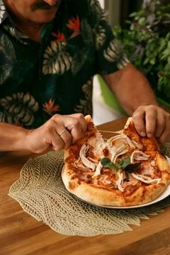 Old man eats pizza in restaurant. Senior stylish modern man with mustage Stock Photos