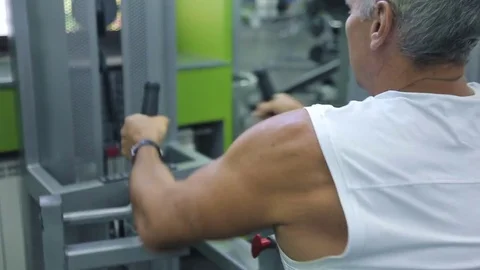 Old man is engaged on simulators in gym Stock Footage