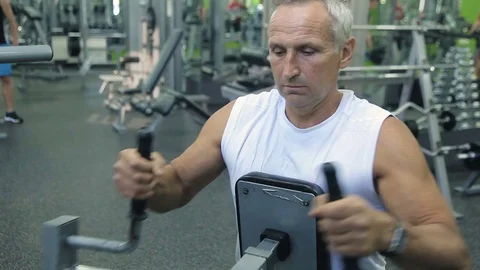 Old man is engaged on simulators in gym Stock Footage 71640256