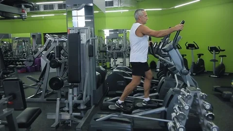 Old man is engaged on simulators in gym Stock Footage 71640433