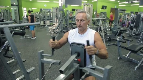 Old man is engaged on simulators in gym Stock Footage 71640858