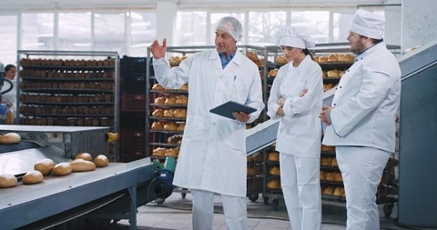 Old man engineer have a chat with two bakers in a bakery industry he explained Stock Footage 112342777