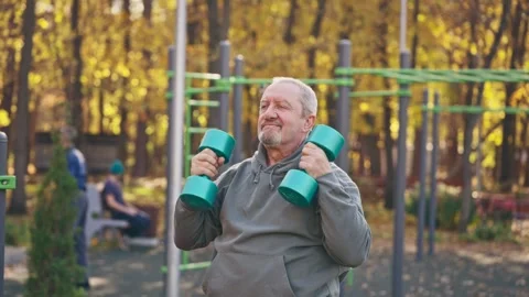 An old man is exercising in a park surrounded by trees and grass Stock Footage 264325173