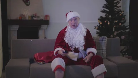 Old man with false white beard in the costume of Santa Claus switching channels Stock Footage 120910800