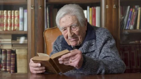 Old  man  focused on reading a book at home Stock Footage 74720567