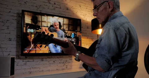 Old man follow online class tutorial to learn to play guitar Stock Footage 138938945