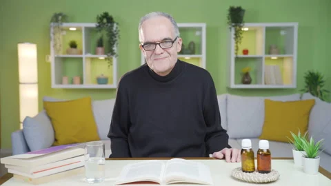 The old man gets emotional while reading a book and drinks from the water. Stock Footage 237786602