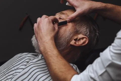 Old man getting his beard shaved by barber Stock Photos