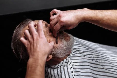 Old man getting his beard shaved by barber Stock Photos