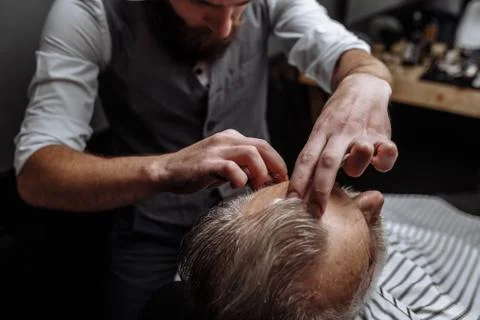 Old man getting his beard shaved by barber Stock Photos