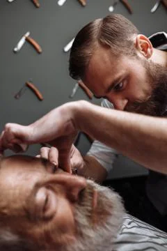Old man getting his beard shaved by barber Stock Photos