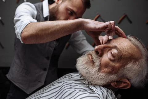 Old man getting his beard shaved by barber Stock Photos